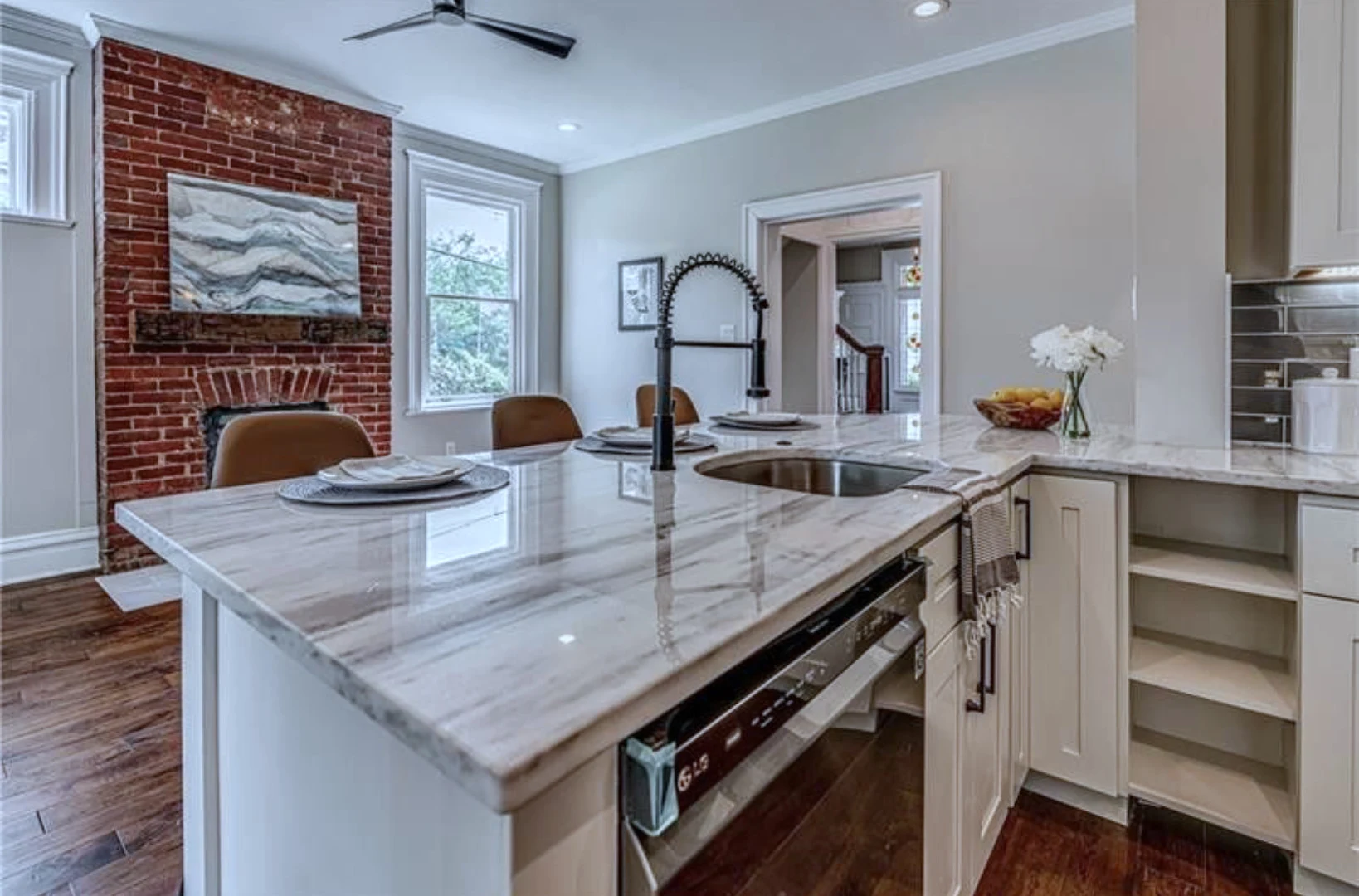 Kitchen — quartz island and exposed-brick fireplace wall