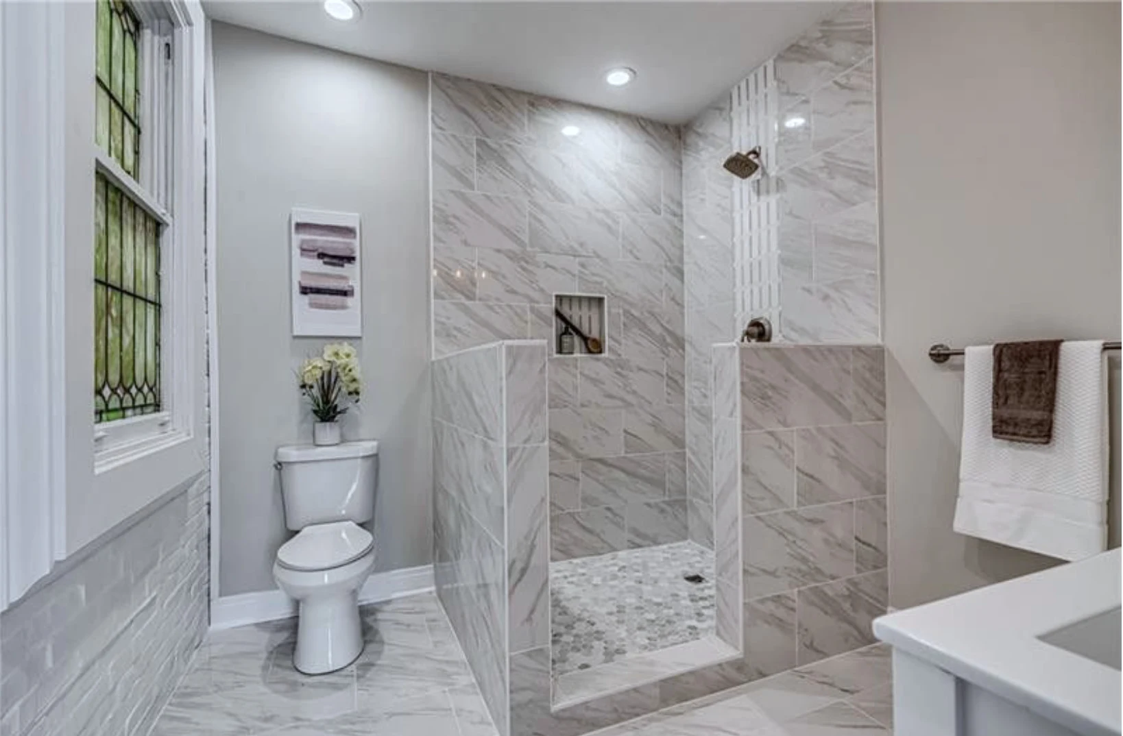 Main bath — walk-in marble shower with preserved leaded-glass window