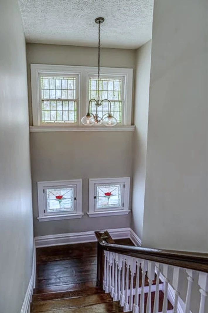 Stair landing — twin stained-glass windows preserved in place