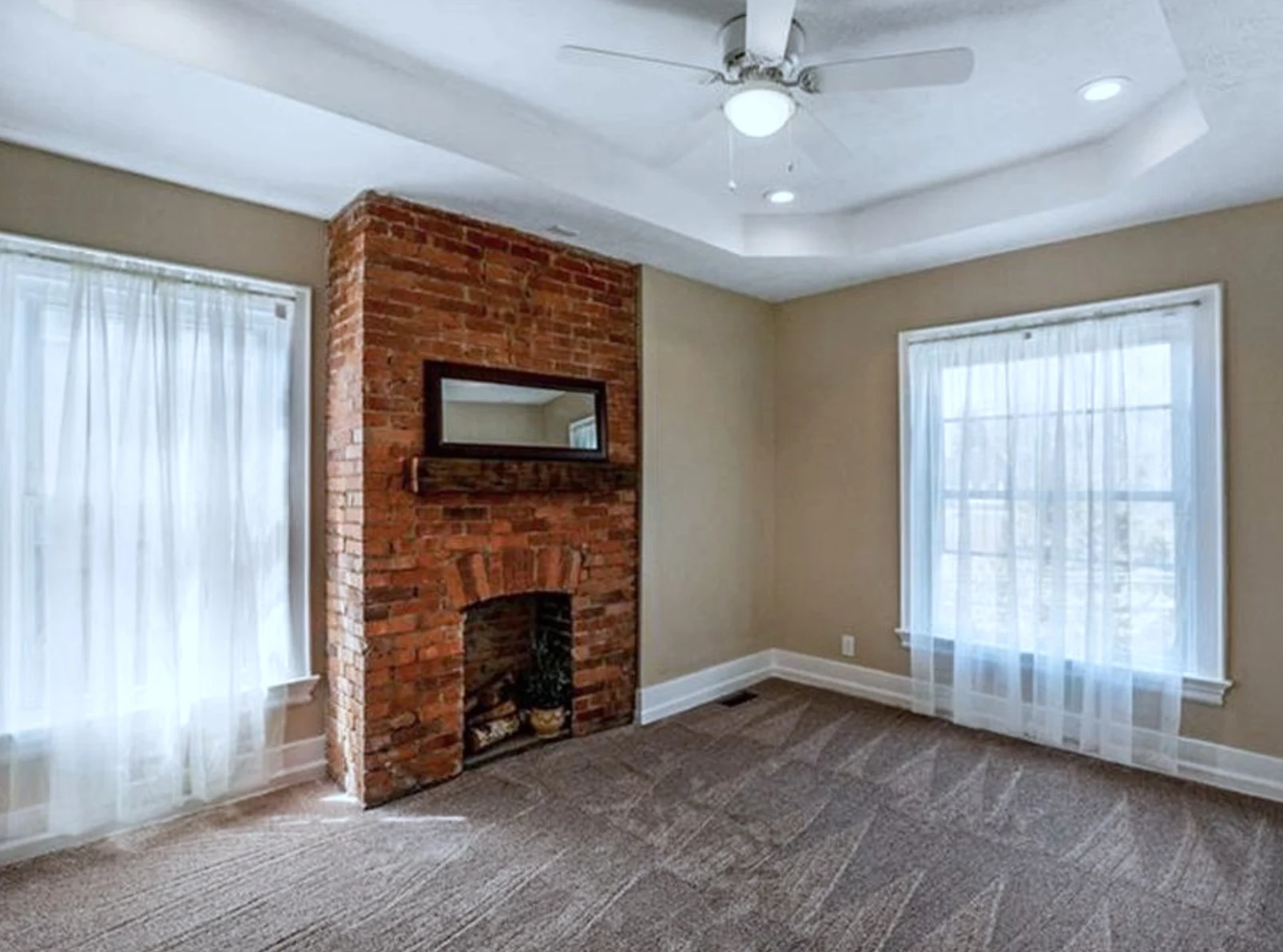 Primary bedroom &mdash; tray ceiling with exposed-brick chimney