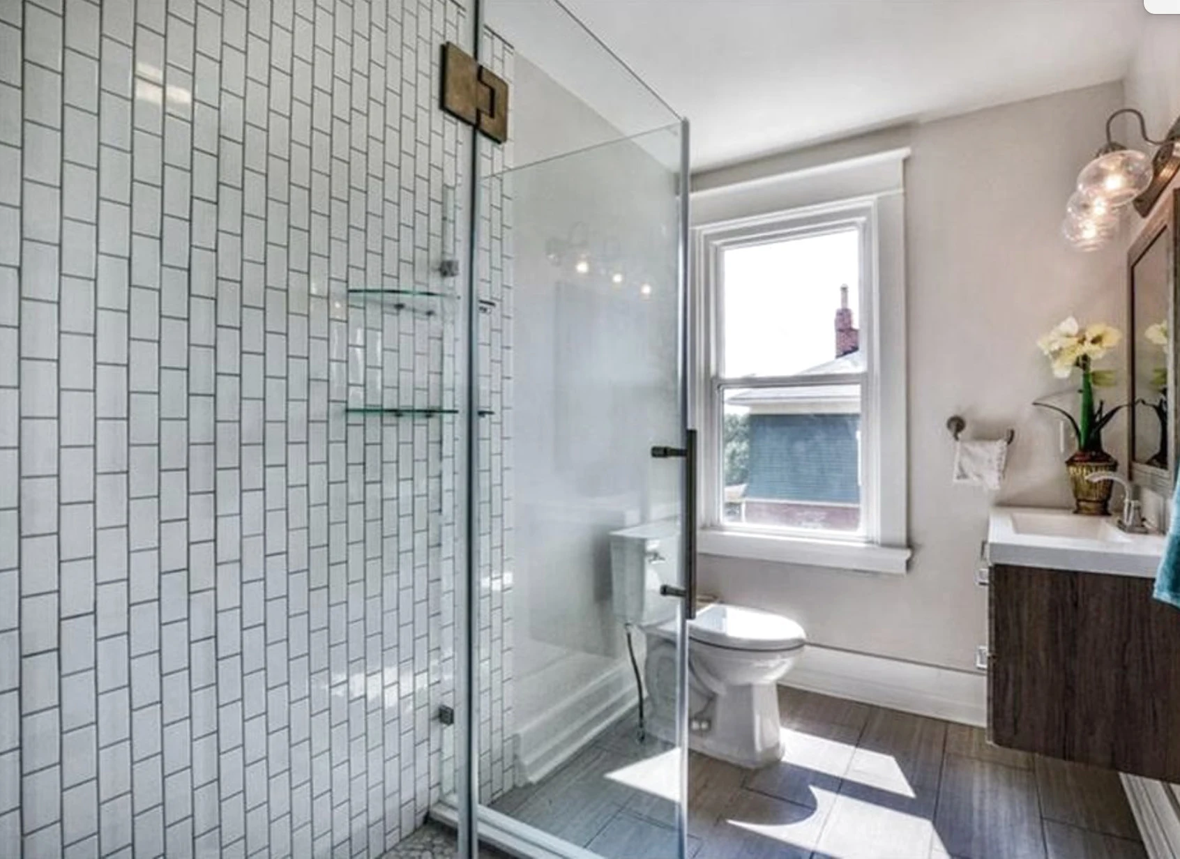 Primary bath — walk-in shower with brass hinges and wood vanity