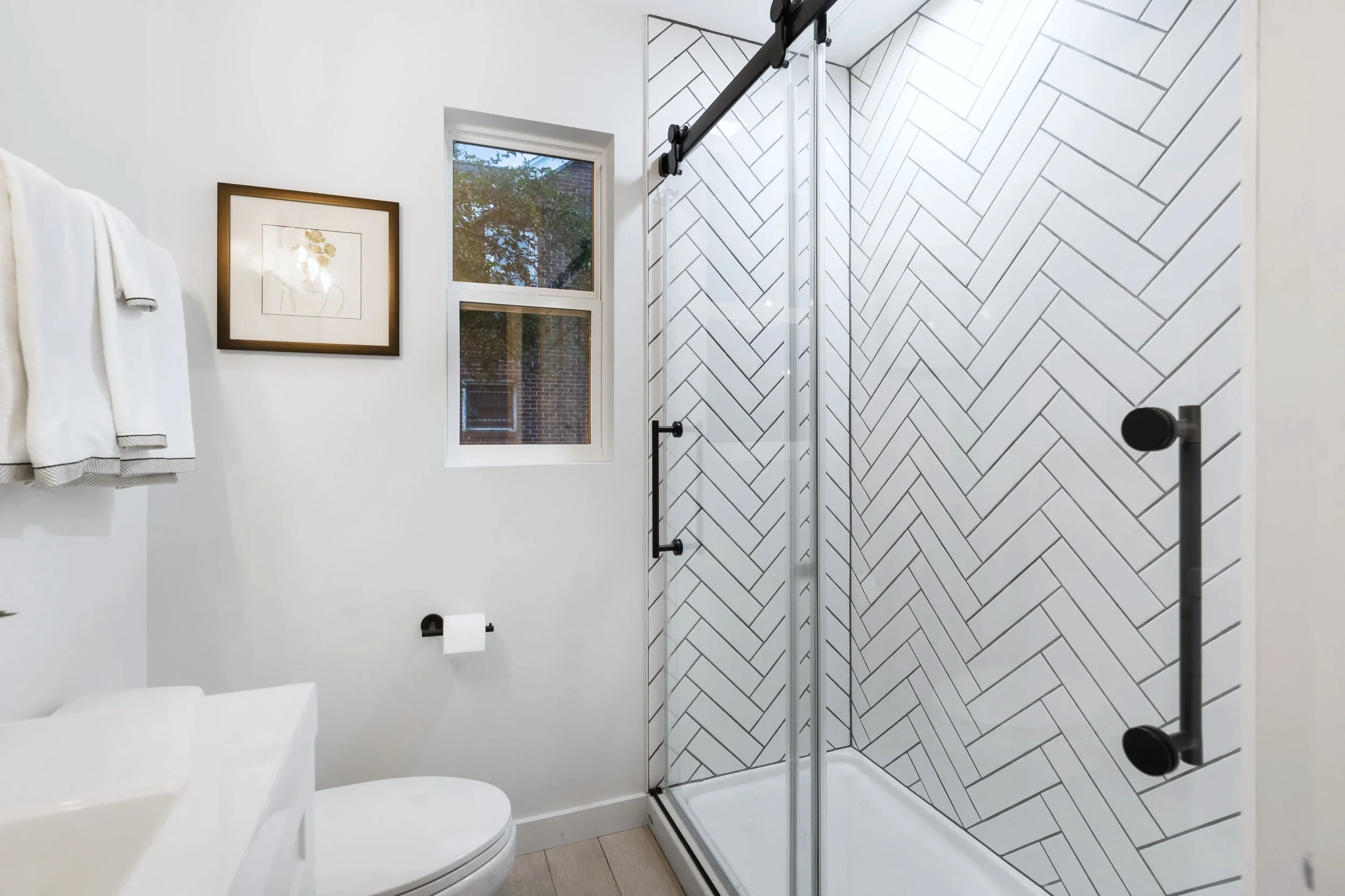Primary bath &mdash; herringbone-tile walk-in shower with barn door entry