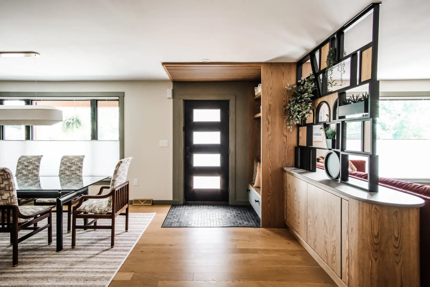 Dining area and front entry with custom white-oak cabinetry and a steel-and-oak room divider
