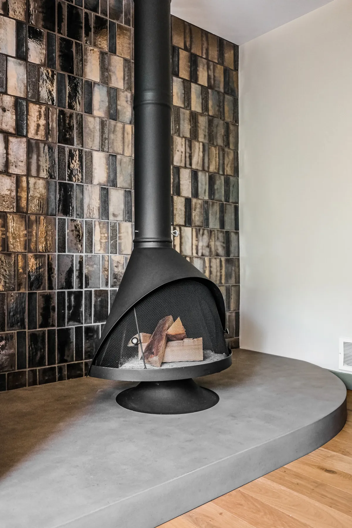 Black Malm fireplace on a curved concrete hearth against glazed dark tile