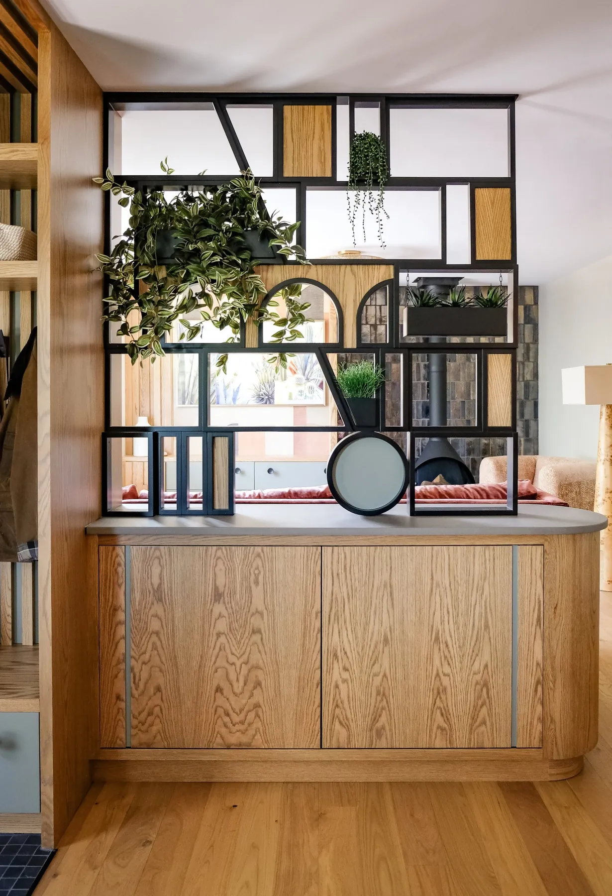 Custom steel-and-oak room divider with arched and circular cutouts over a white-oak base cabinet
