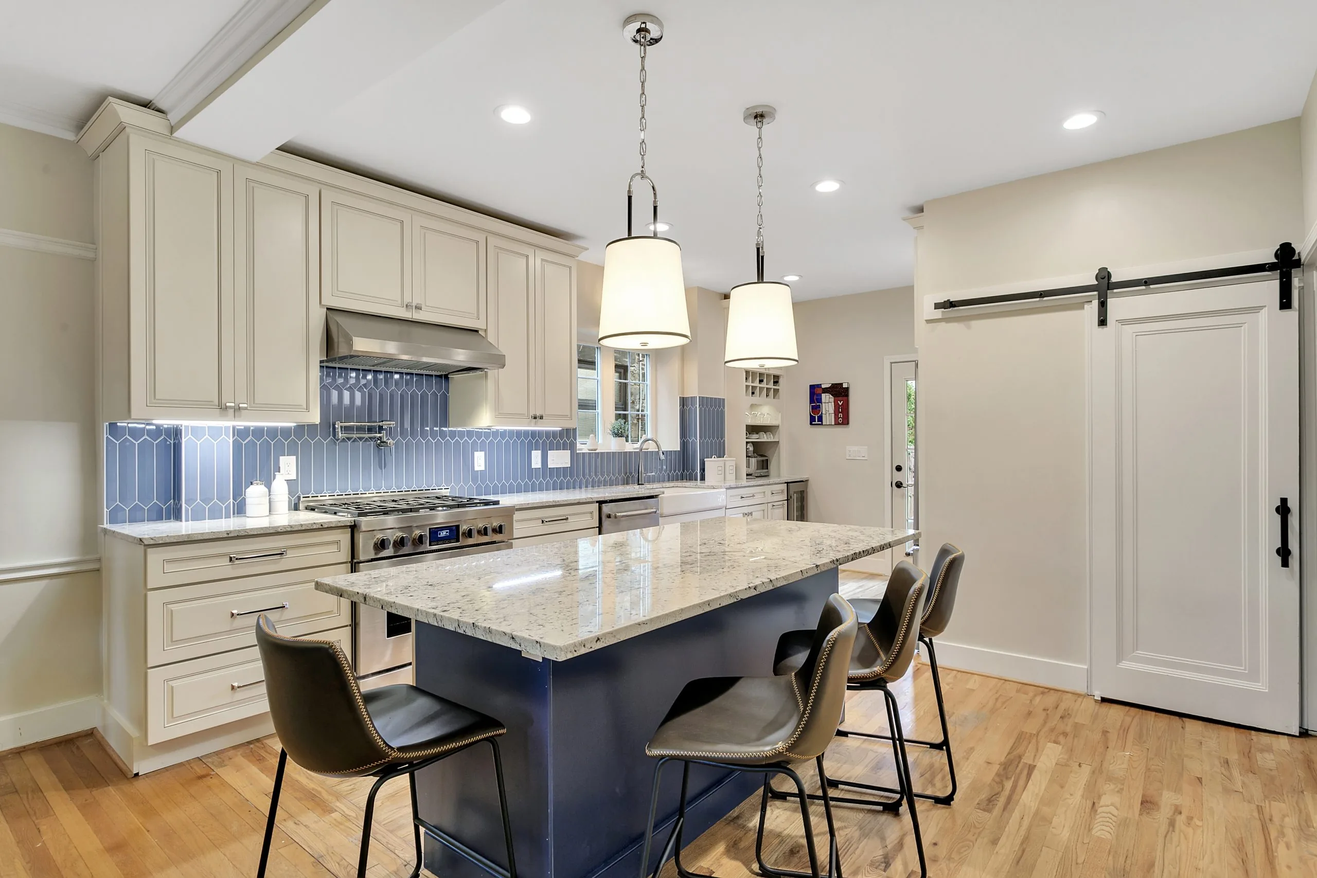 Open kitchen with a navy island, marble counters, and pendant lighting in Point Breeze